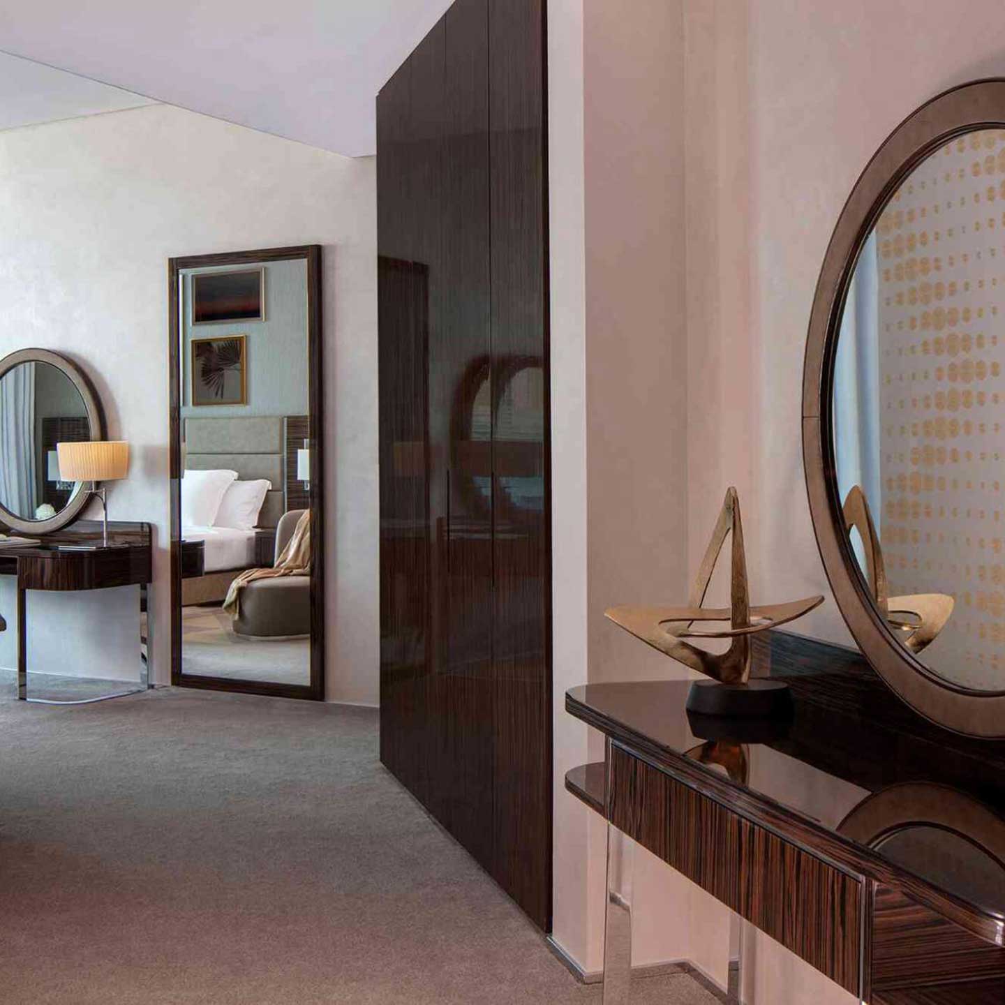 Dresser table with a mirror in the forefront, built in wardrobe, then a floor mirror and a console table in the background