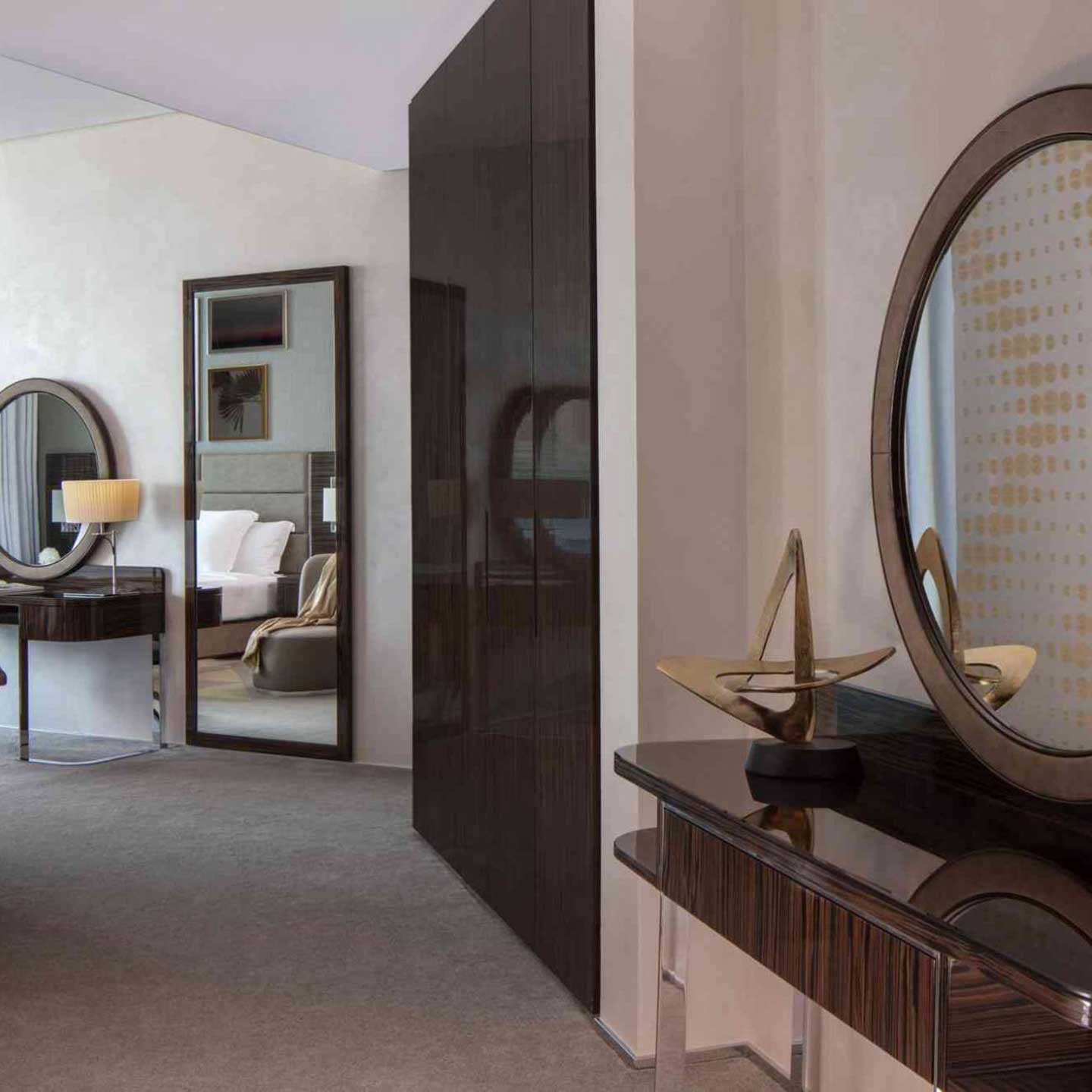 Dresser table with a mirror in the forefront, built in wardrobe, then a floor mirror and a console table in the background