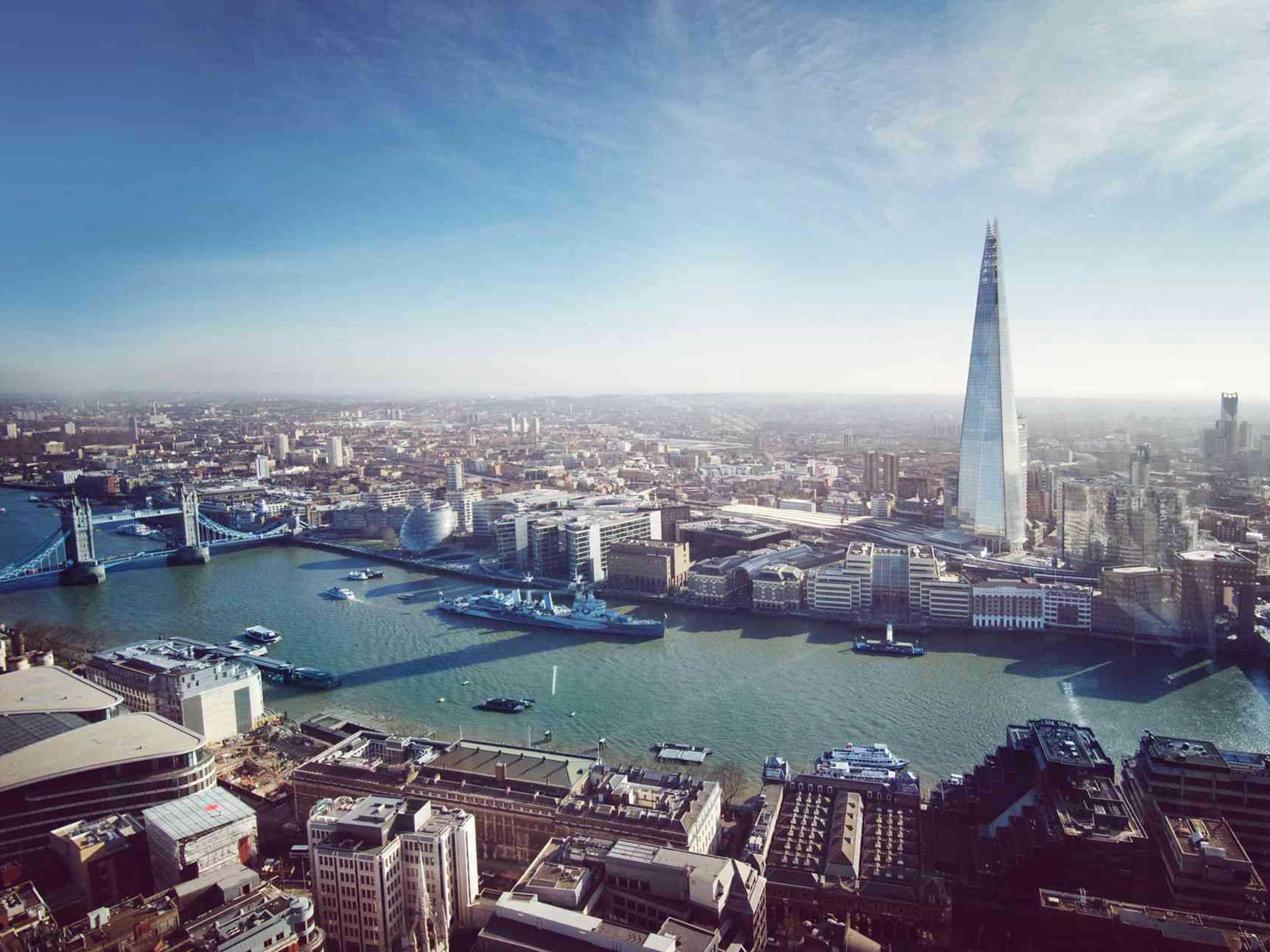 Aerial view of The Thames on a blue sky day, with Tower Bridge, The Shard and other well known London sites