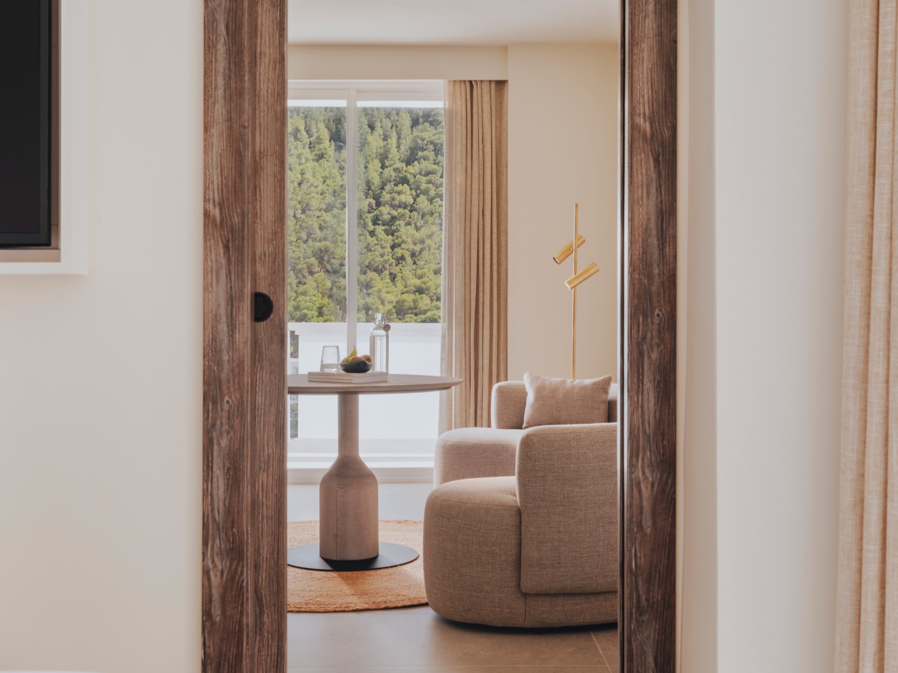 A large wall mirror reflecting a curved couch and coffee table in the forefront, and balcony view in the background