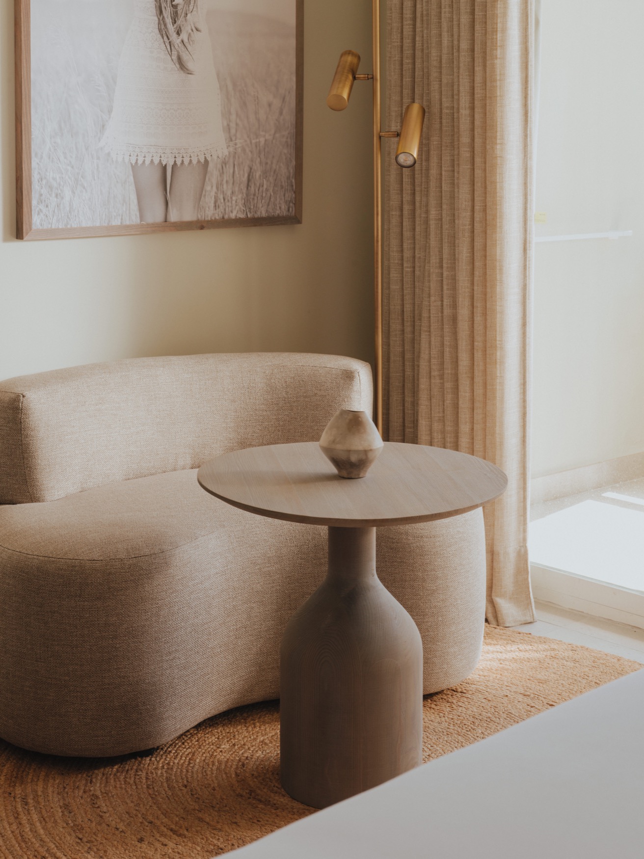 A curved 1 seater coach with a round coffee table, and a floor lamp in the corner