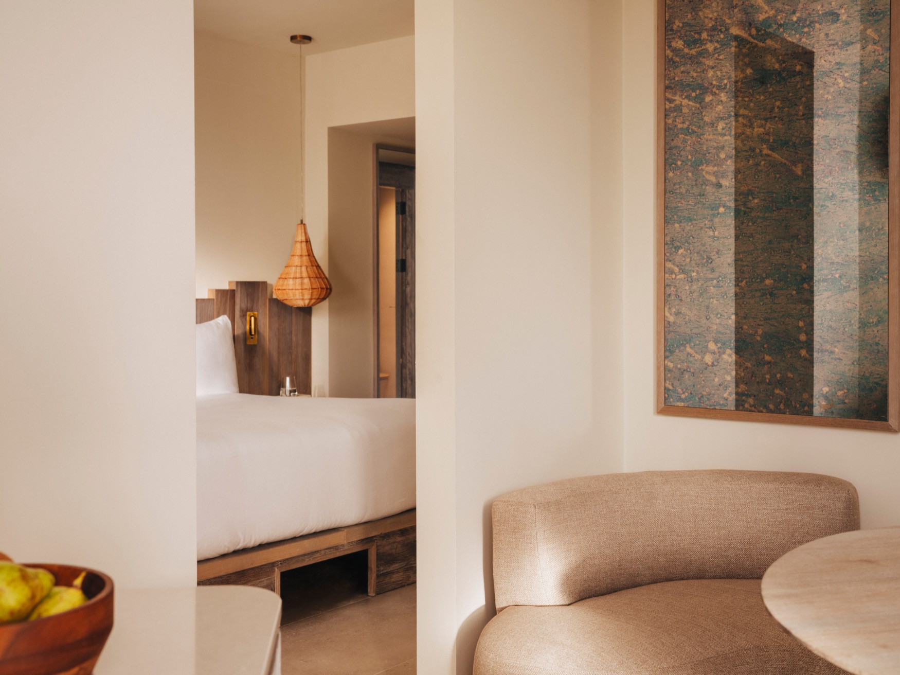 An armchair with coffee table in the forefront, with a partial view of the double bed, ceiling lamp and bathroom door in the background