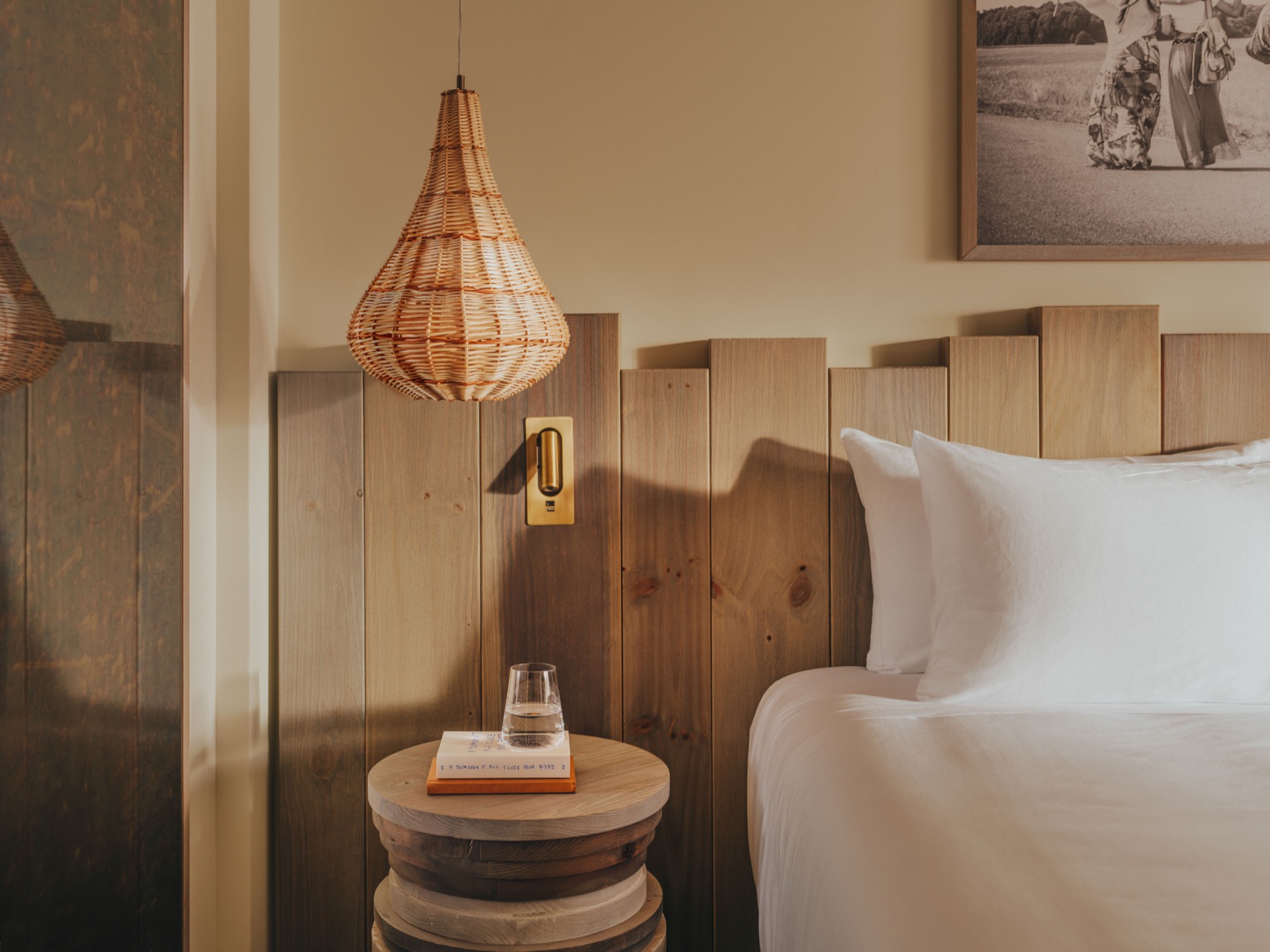 A view of the bedside table and a lamp hanging from the ceiling in the centre with a part of the double bed visible on the right