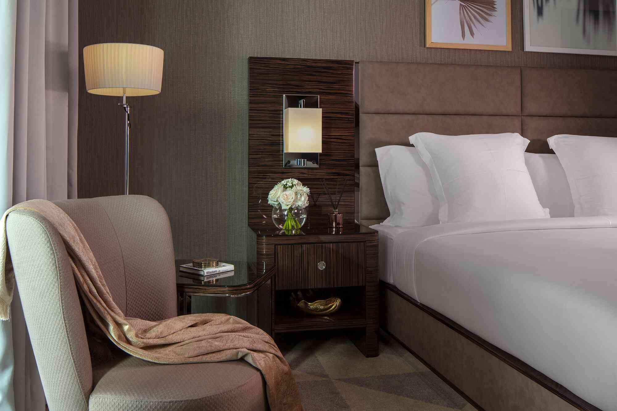 Hyde Dubai Chambre General Admission King montrant un lit King avec des tables de chevet, un fauteuil confortable avec un plaid et un lampadaire