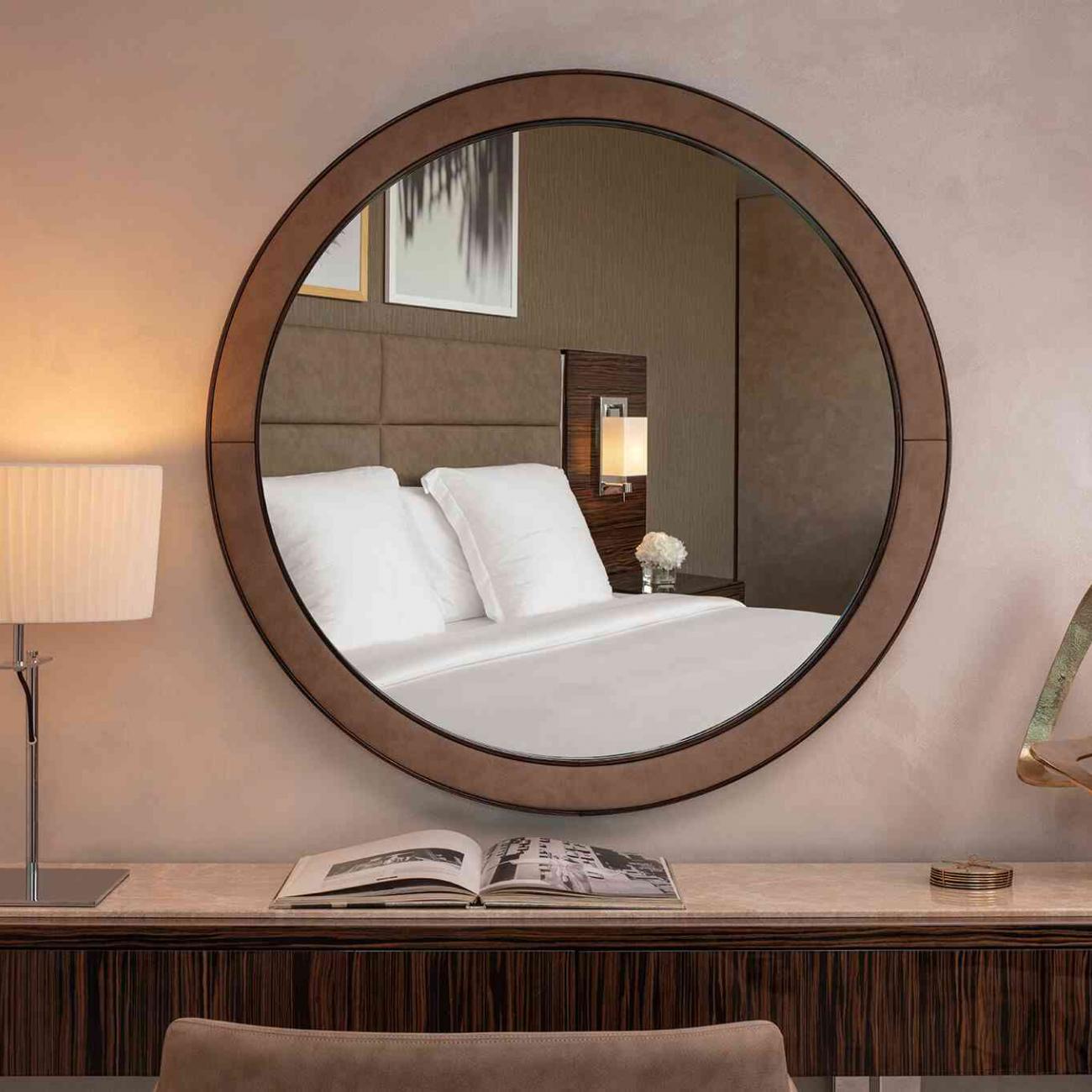 Coiffeuse avec lavabo, et miroir mural rond qui renvoie l'image d'un lit double