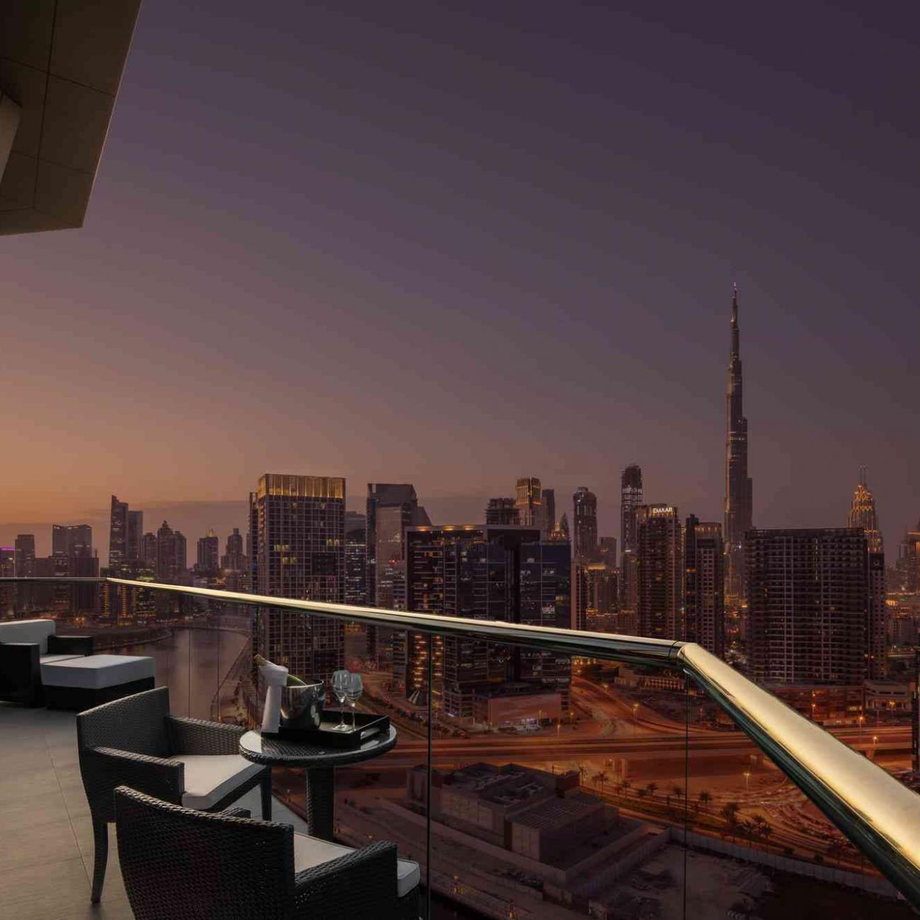 Vue d'un balcon avec 2 chaises et une table basse surplombant Dubaï