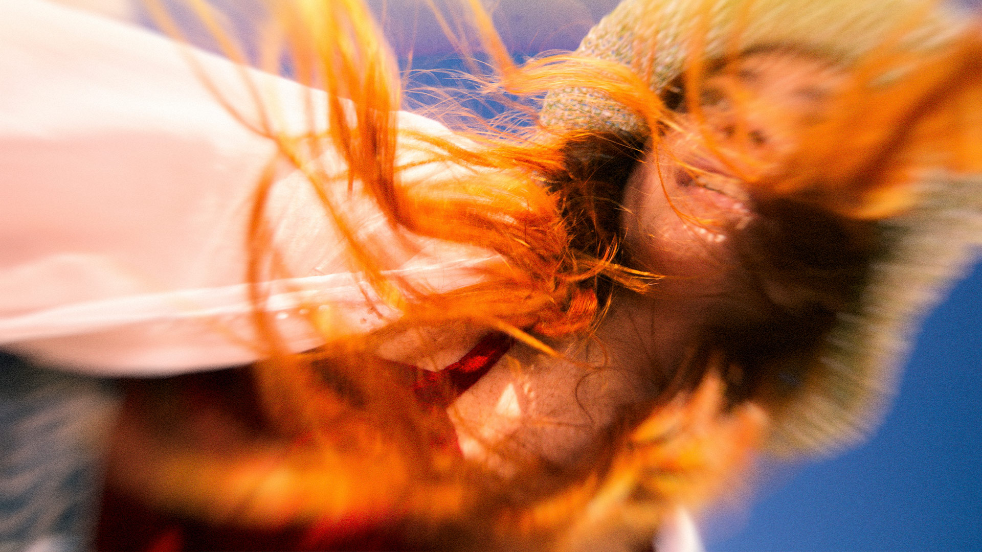 Femme rousse souriante, les cheveux pendant d'un chapeau de paille havane