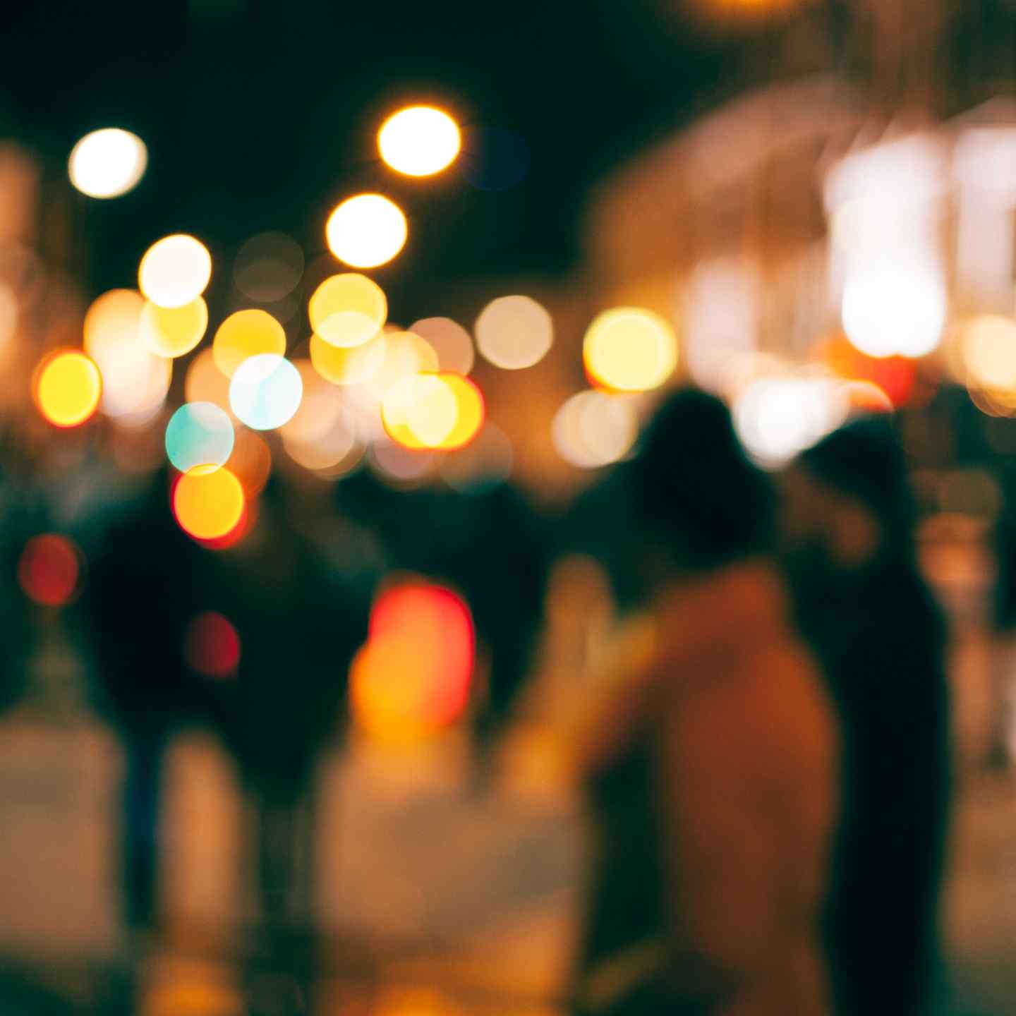 Décor urbain flou avec des personnes marchant dans la nuit et des phares en arrière-plan