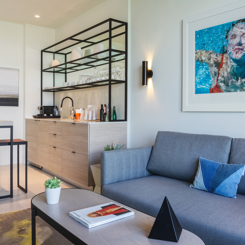 Living area of a hotel room, with blue sofa and coffee table