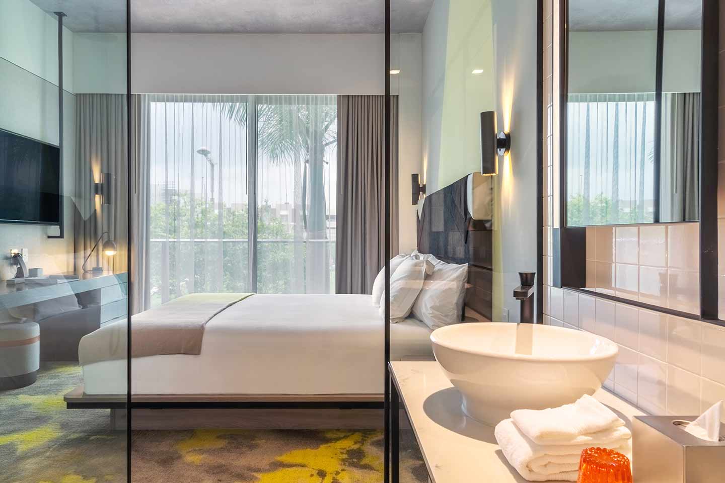 Chambre à coucher au Hyde Midtown Miami avec lavabo au premier plan et cloison en verre