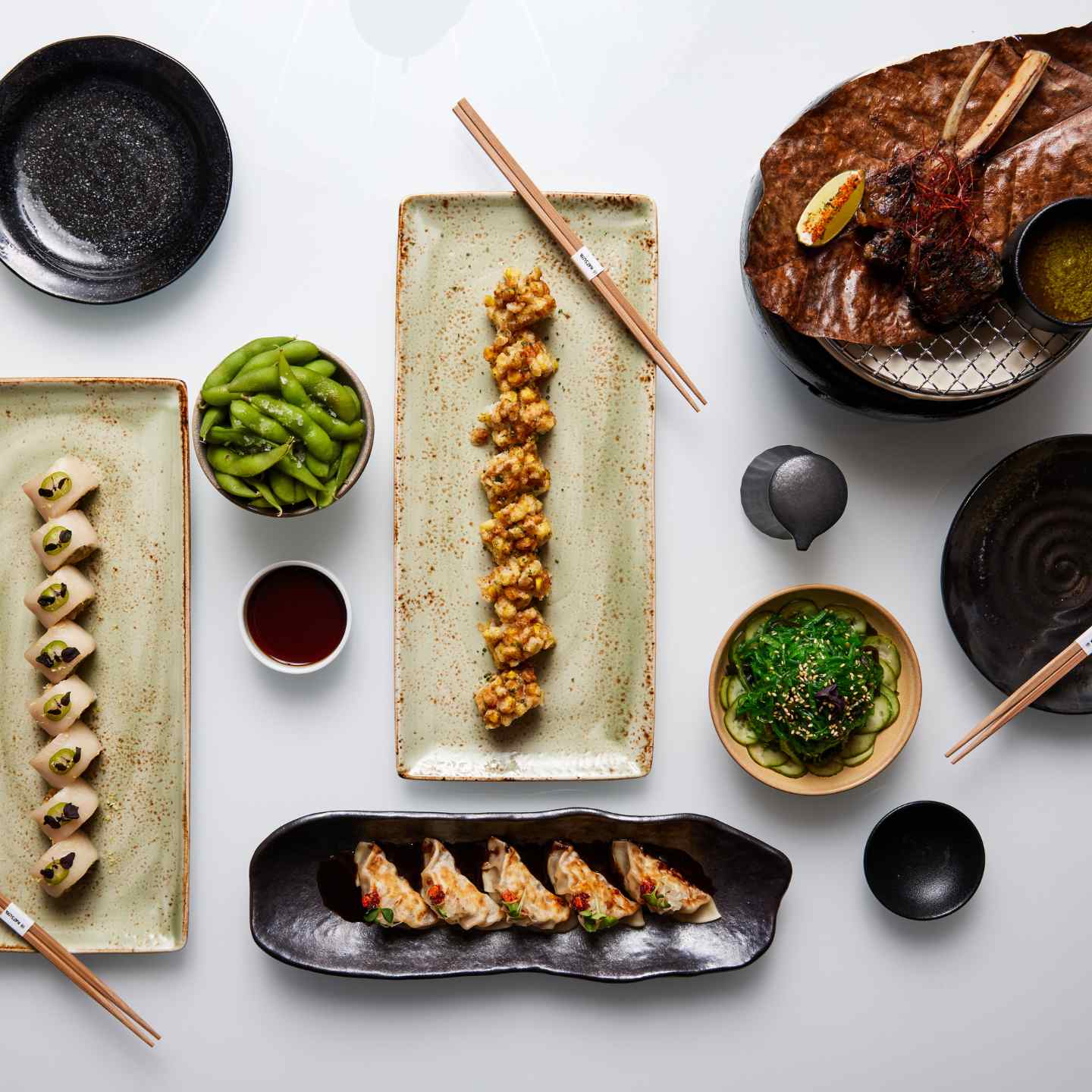 Sushi rolls on various plates and beef on a round plate