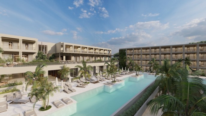 Large rectangular pool with lounge chairs, palm trees, and a white large building behind the pool and a dark building to the right of the pool