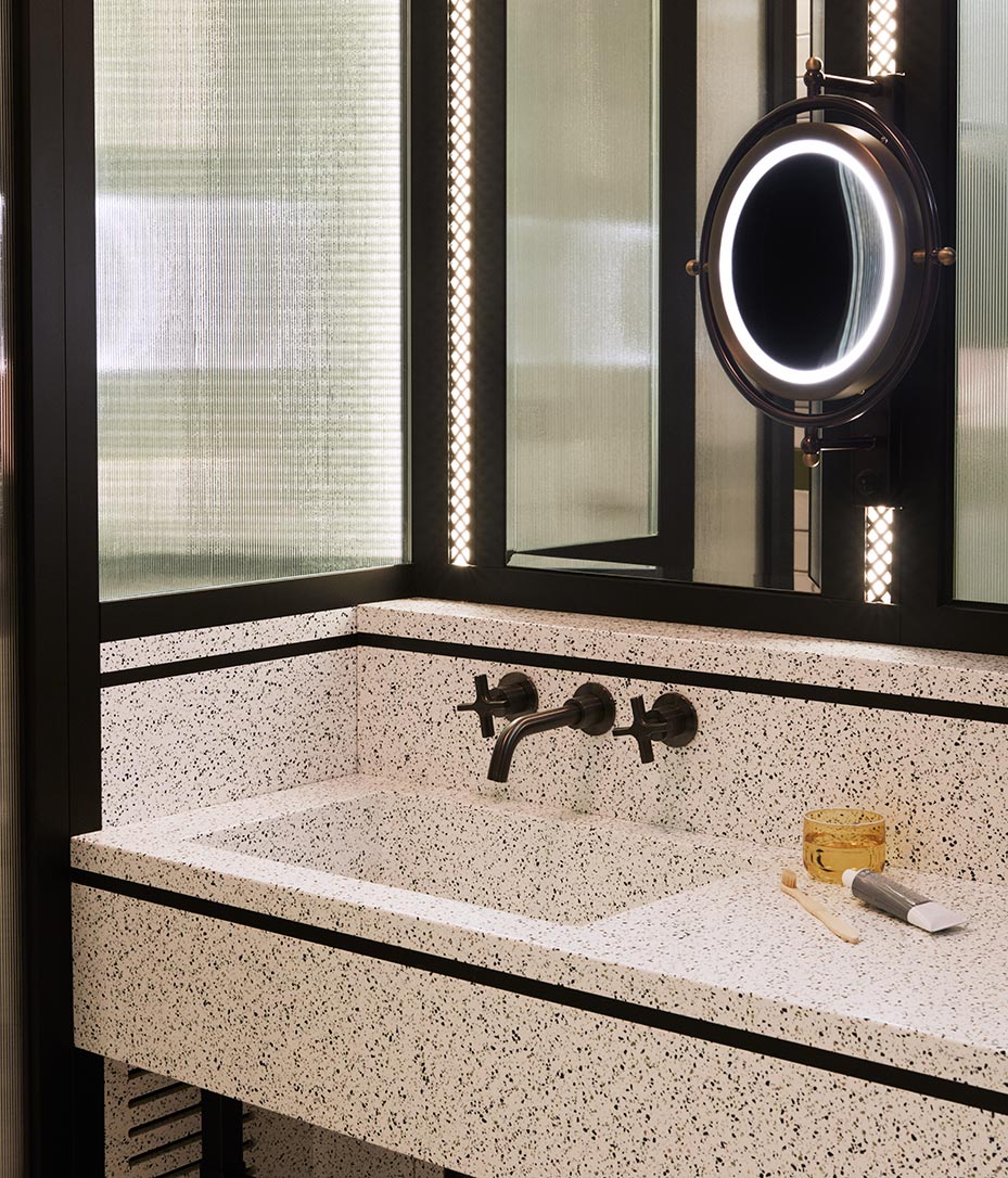 Large white bathroom sink with black detailing and small round mirror