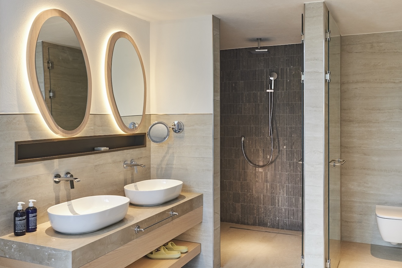 Double sink with circular mirrors and shower in the background