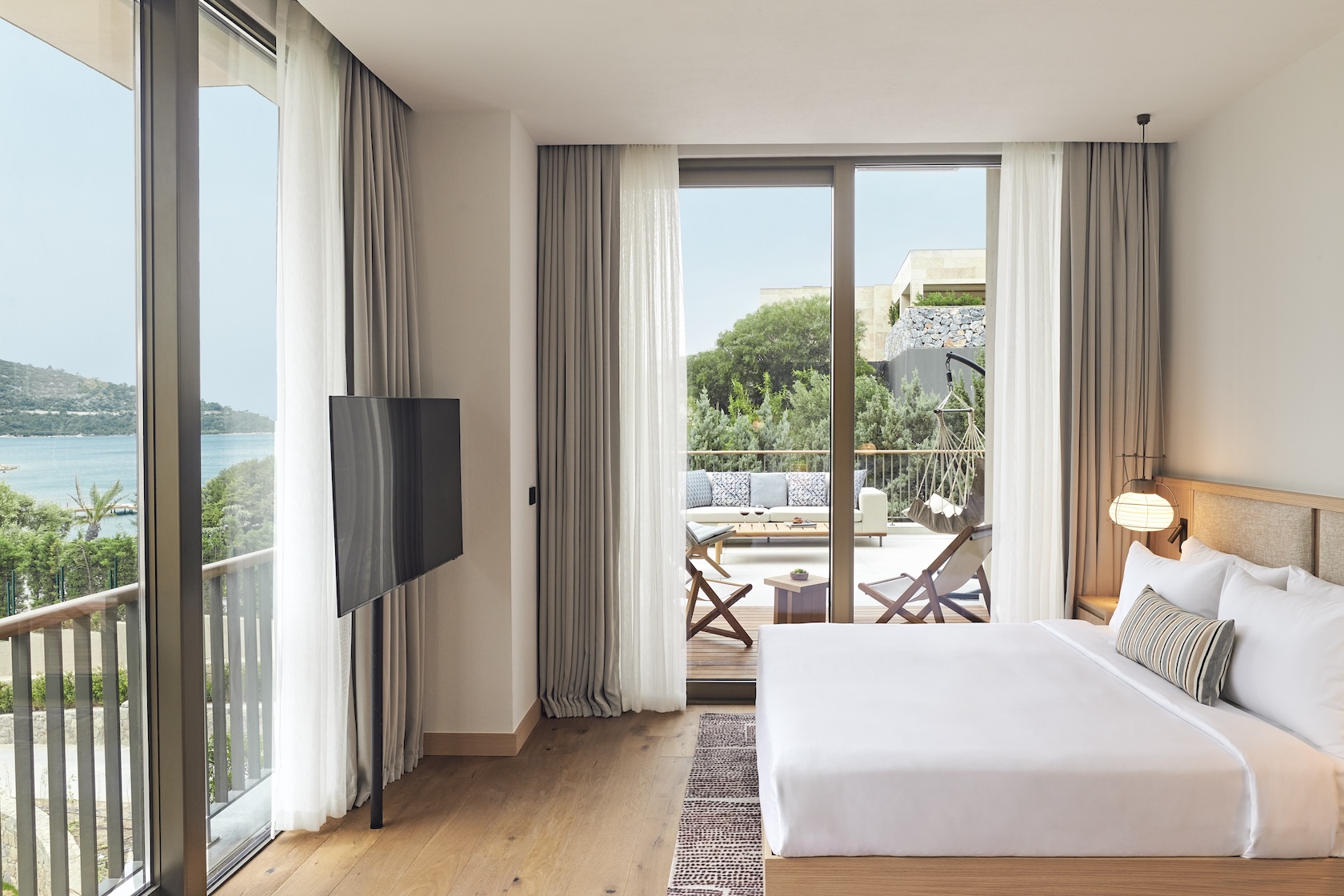 Large bed in a corner suite with two large glass sliding doors on both walls