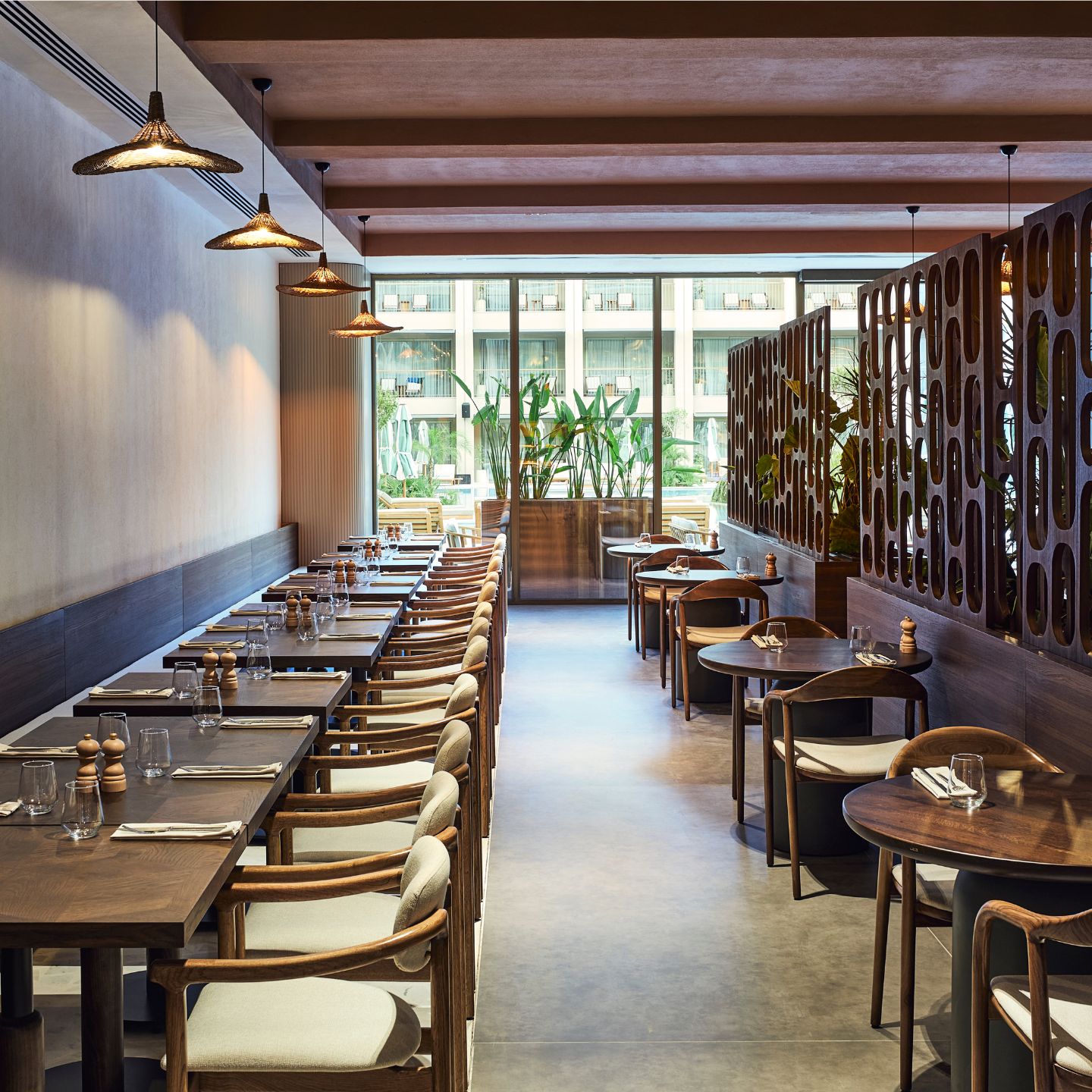 Dining room with row of square wooden tables and row of round wooden tables
