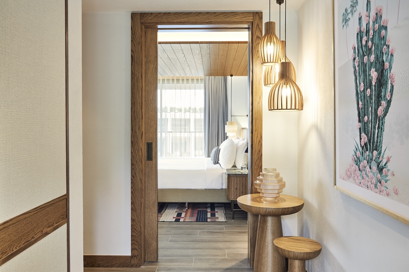 Open door with small tables, pendant lights, and framed artwork on the wall