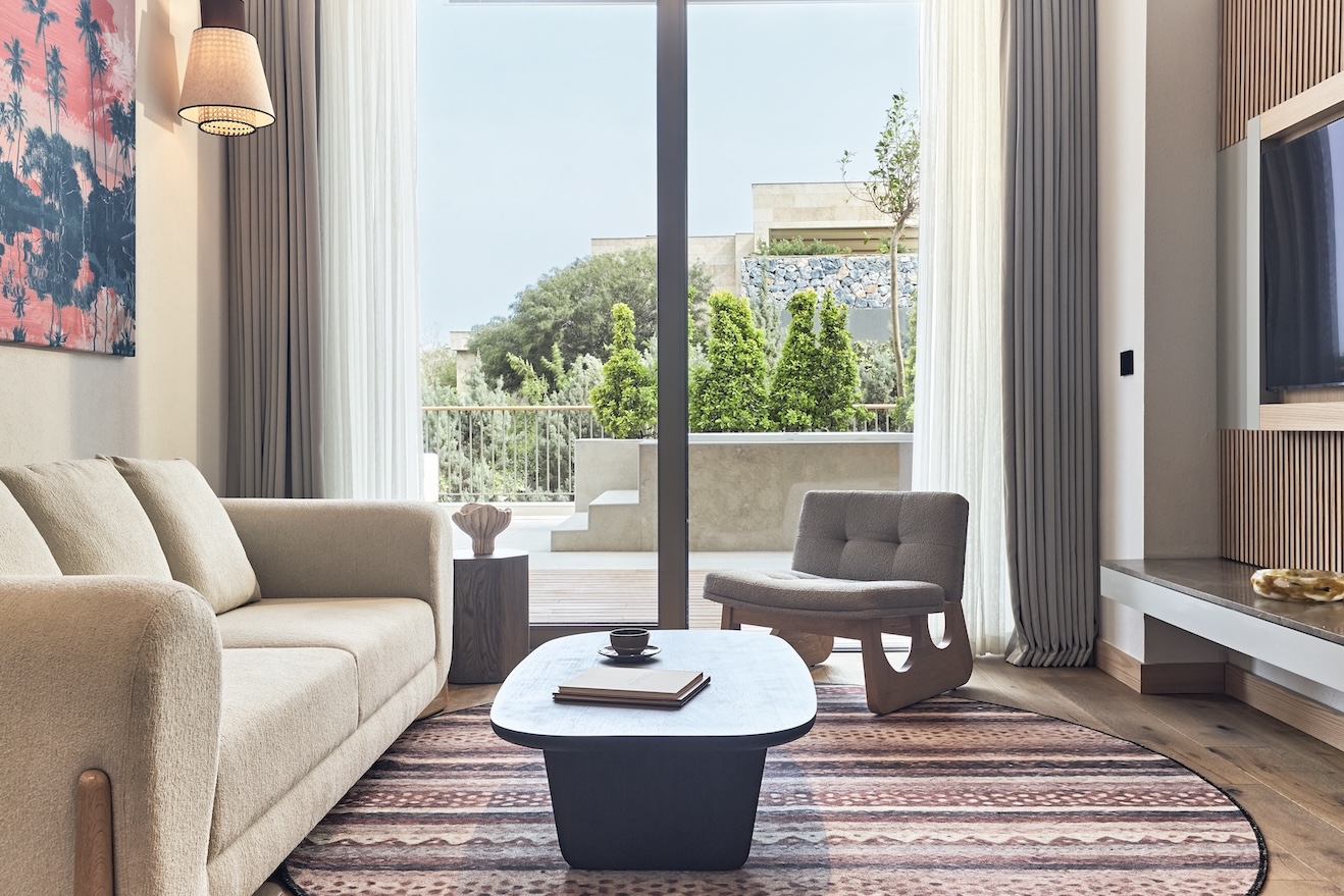 Beige sofa with coffee table on patterned rug and small chair in the corner with large glass doors