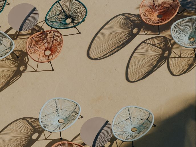 Clusters of round circular outdoor chairs on a cream patio ground