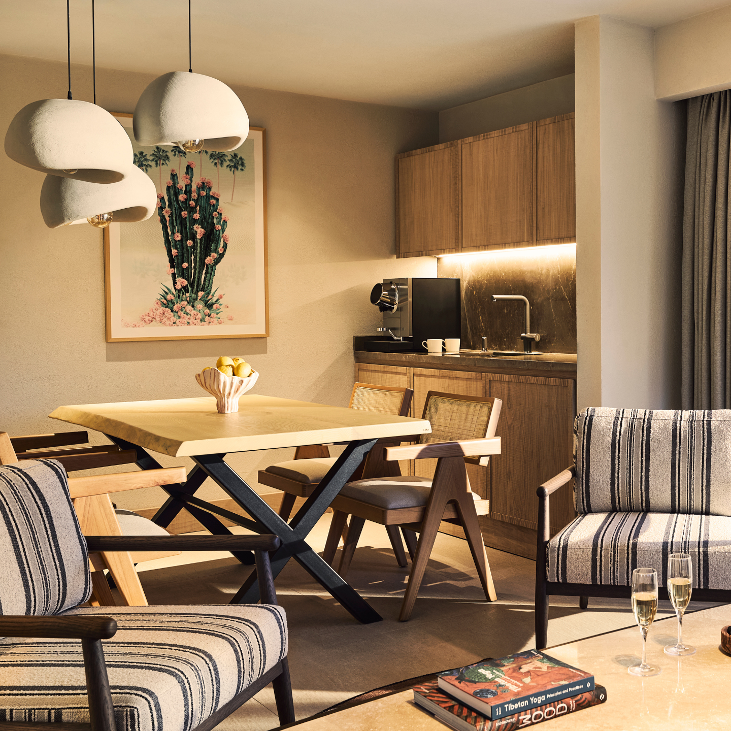 Hotel room interior featuring dining and relaxation area with kitchen in the background