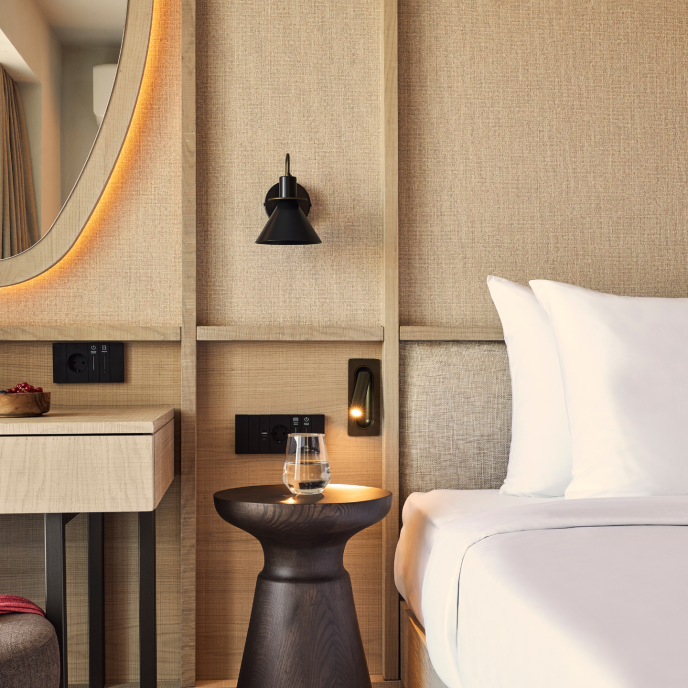 Hotel room with a bed, side table with a glass and desk with mirror