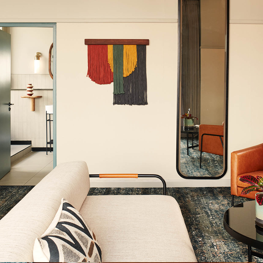 A full-length mirror on the wall, next to the hanging wall art. The 3-seater couch is in the centre of the image.