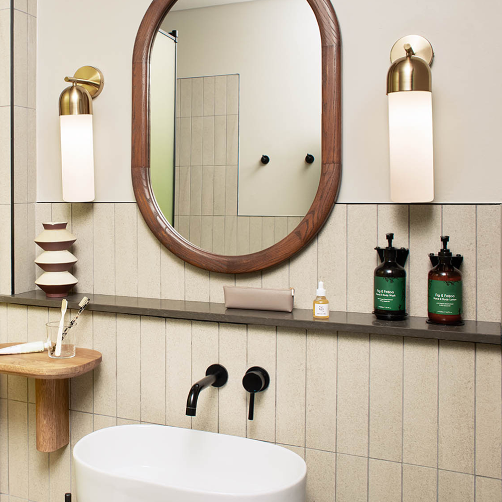 A white sink, with the mirror hanging on the wall, and lights mounted on each side of the mirror.
