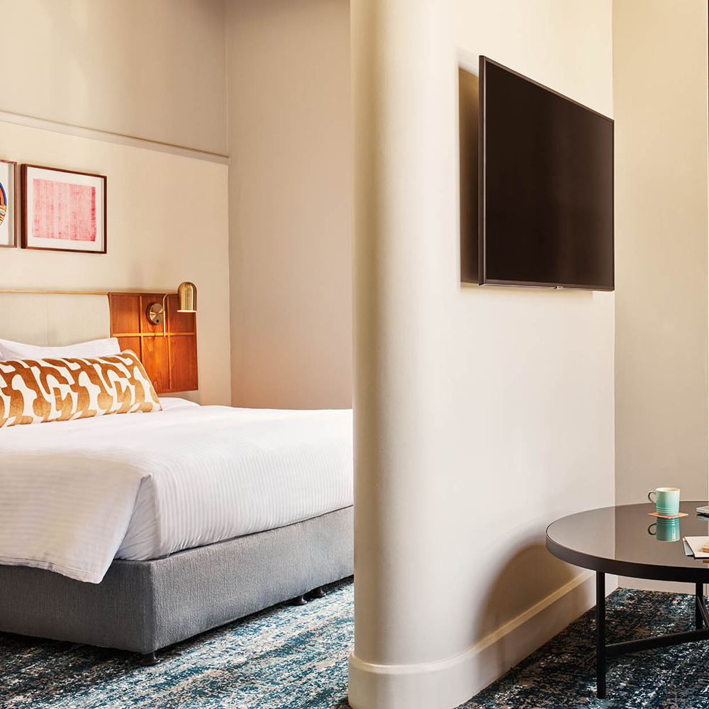 A king-sized bed in the back, with a pillar and TV mounted to the pillar