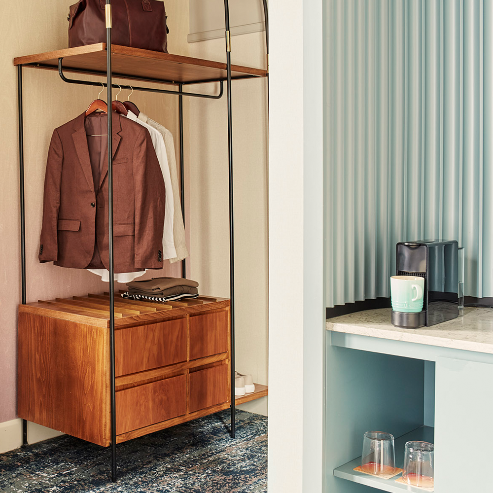 An open wardrobe with wooden drawers on the left of the image, the tea/coffee station with the Nespresso machine on the right of the image.
