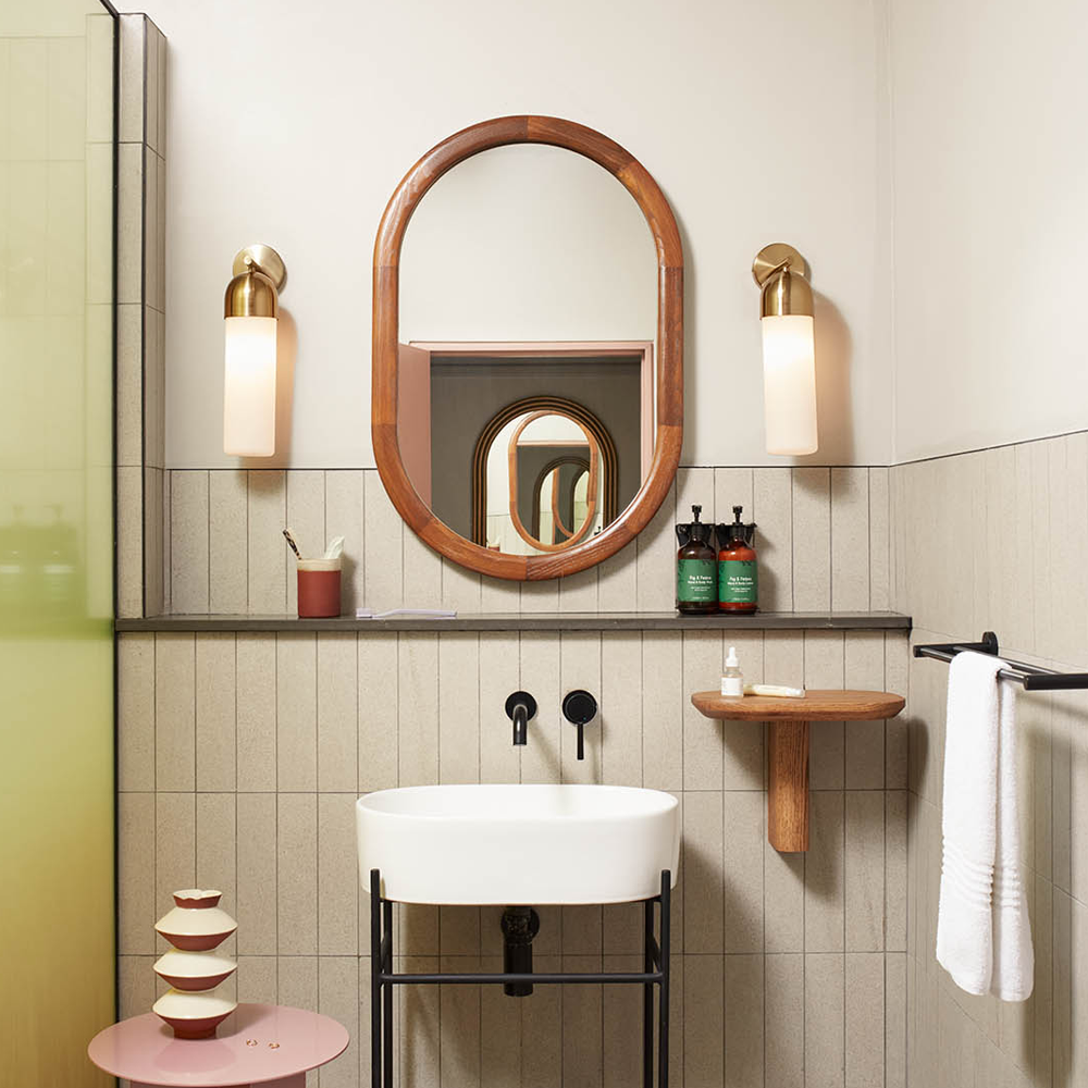 A bathroom with a walk-in shower on the left of the image, a basin and mirror in front, with additional place to put your accessories.