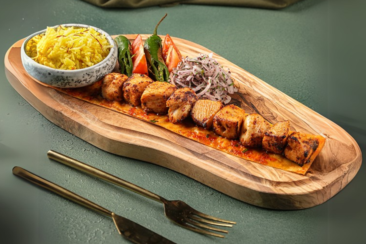 Middle Eastern Chicken Dish on a wooden tray with rice and vegetables