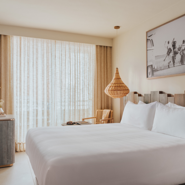 A bedroom with large bed and decorative light and artwork above
