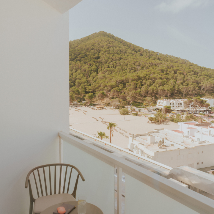 Chair on the balcony overlooking trees and mountains in the distance