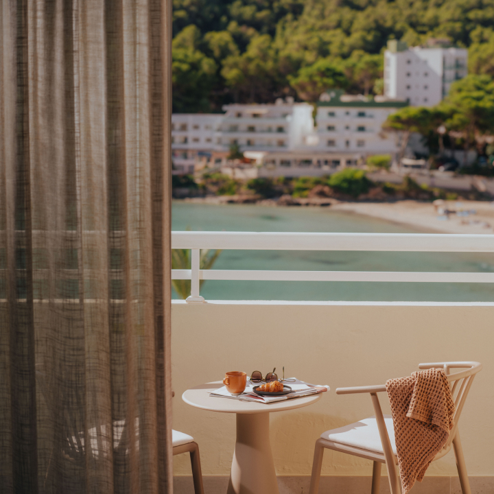 A balcony with two chairs and a table overlooking the sea