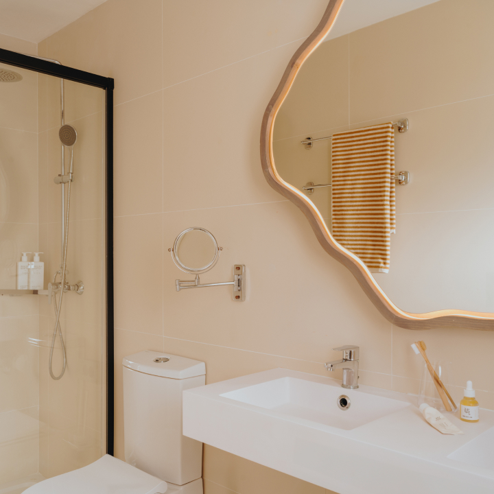 A bathroom with large mirror and sink, plus shower