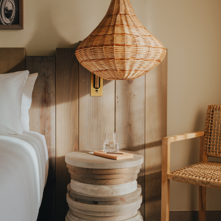 A side table with decorative light overhead, next to a double bed and armchair