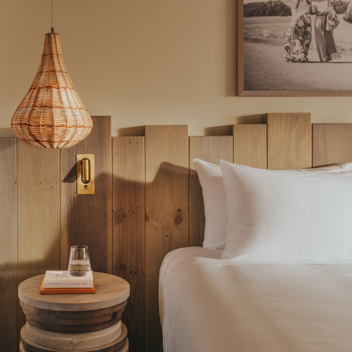 A bedroom with bed, wood panelling, side table and decorative light
