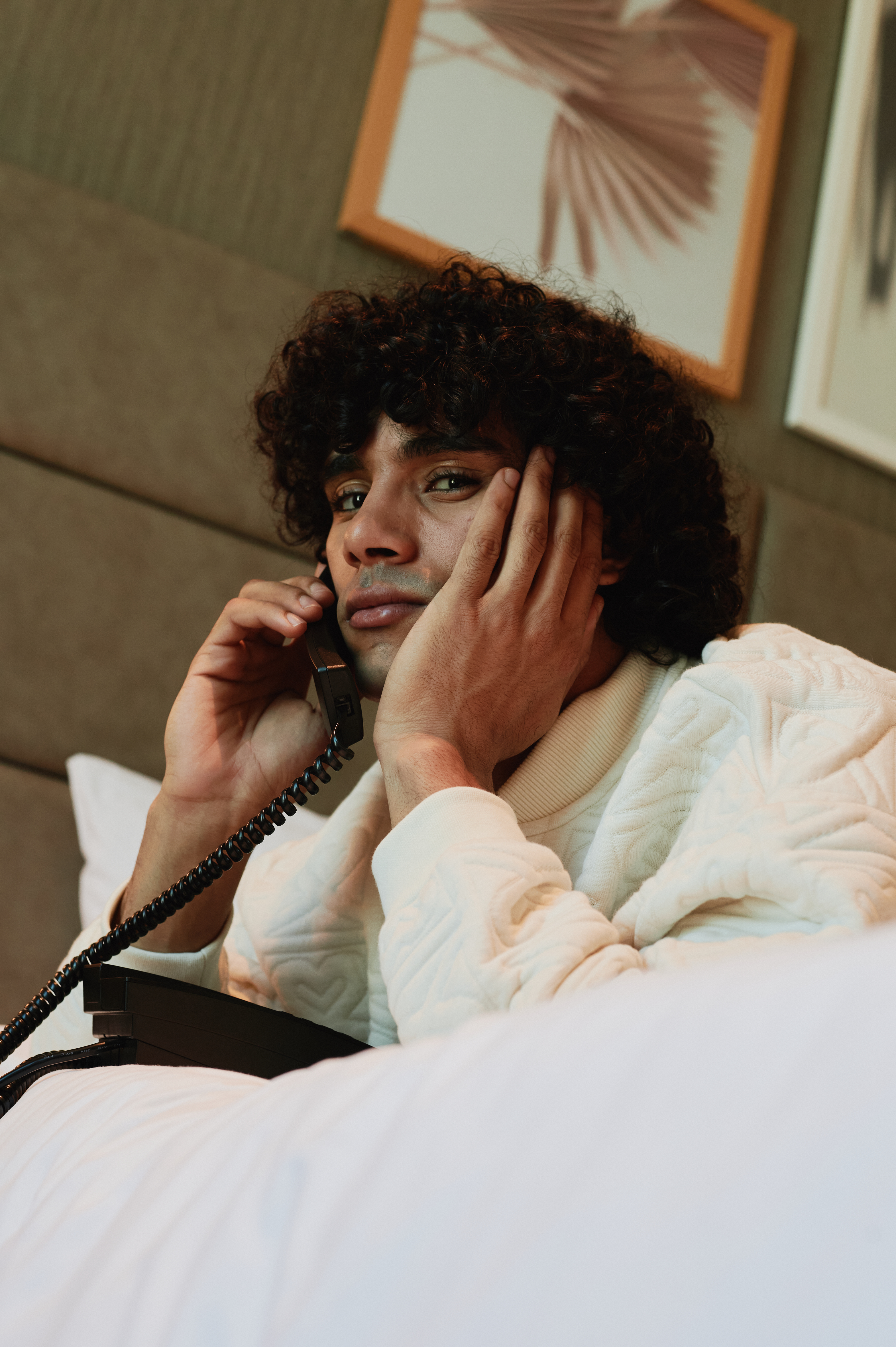 A man lying in bed, speaking on the phone