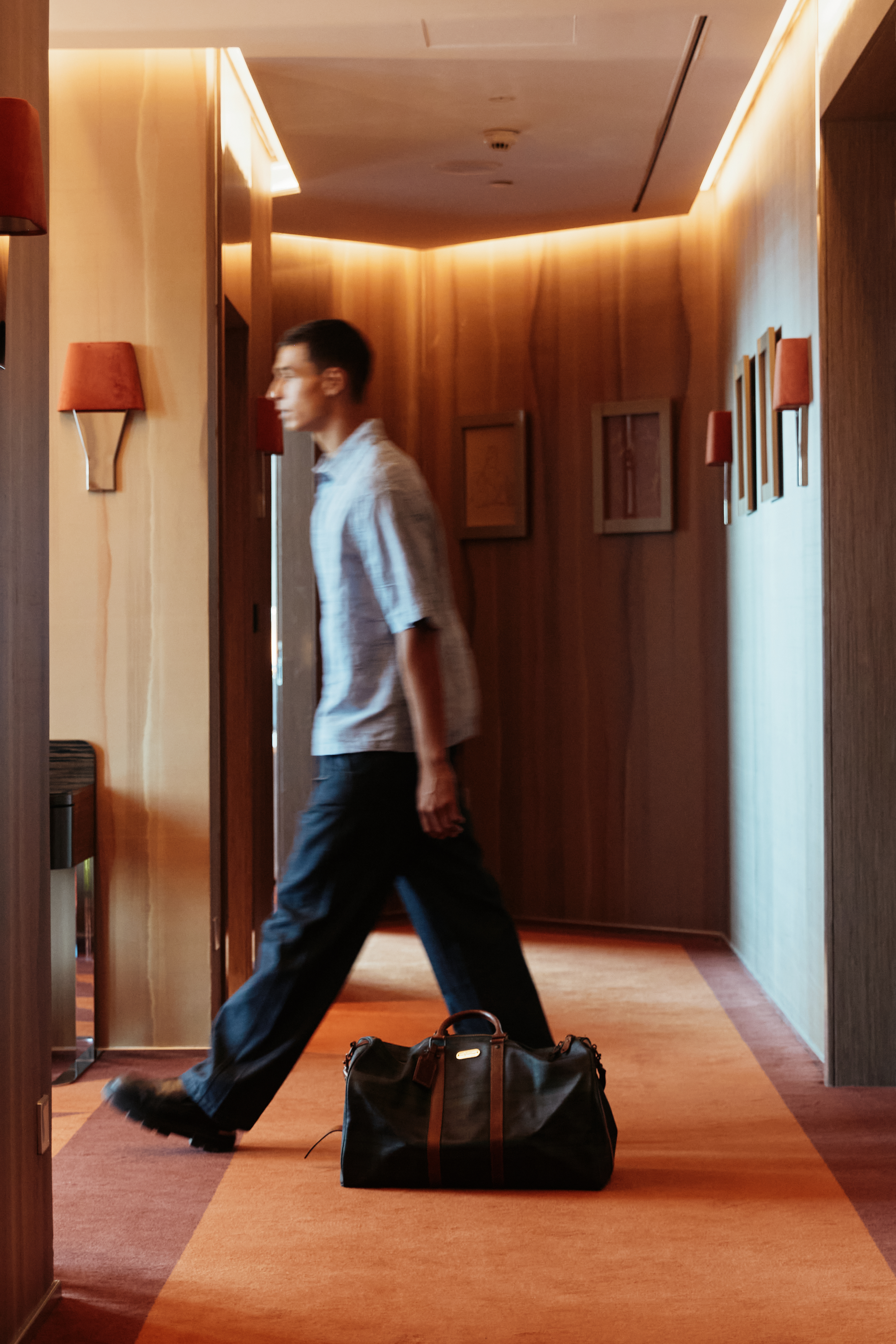 A man entering a hotel room, carrying a travel bag.