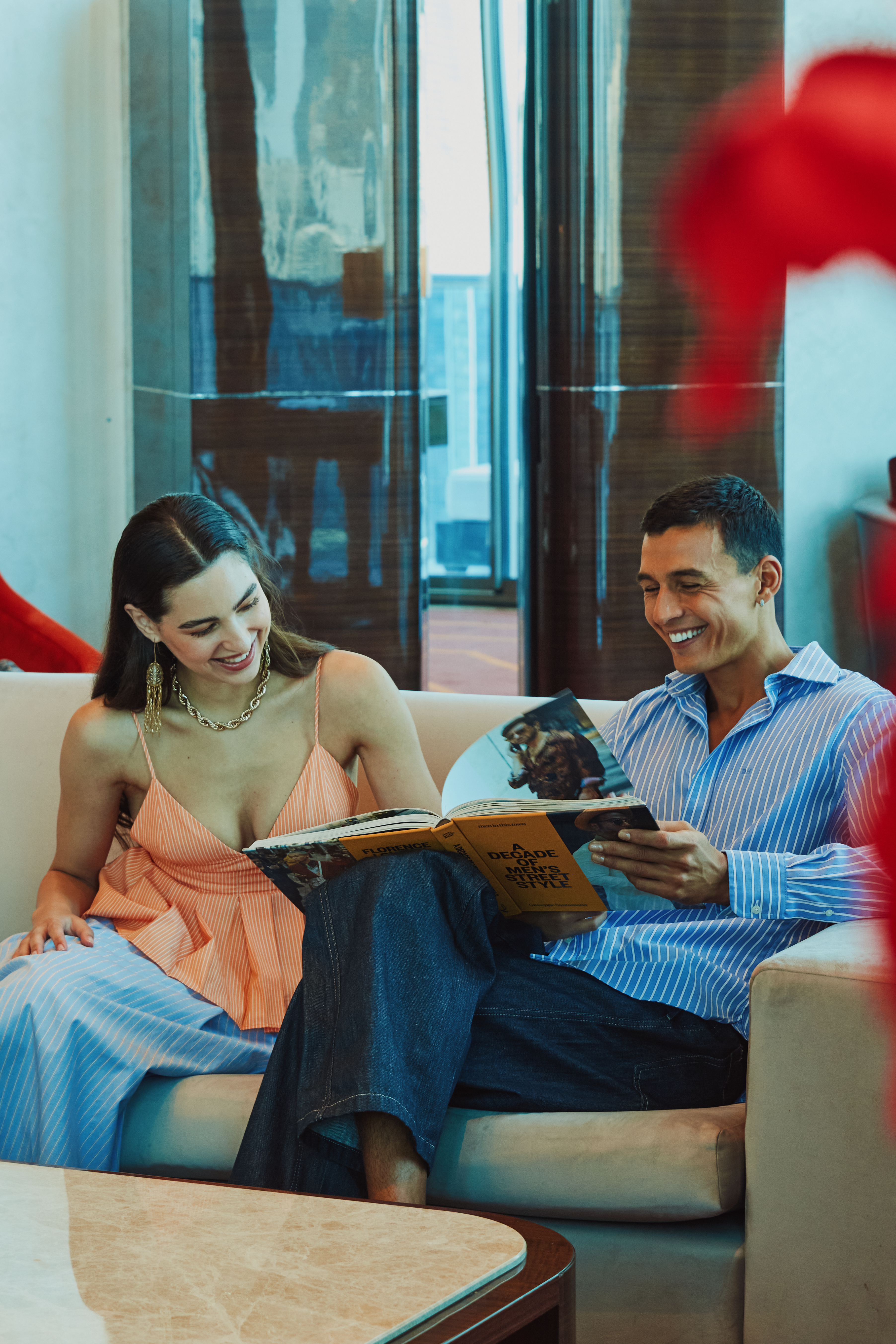 A happy couple, a woman and a man, sitting on a sofa in the living room, reading a book together.